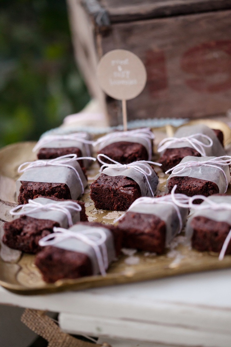 a table topped with lots of brownies covered in icing next to a wooden box