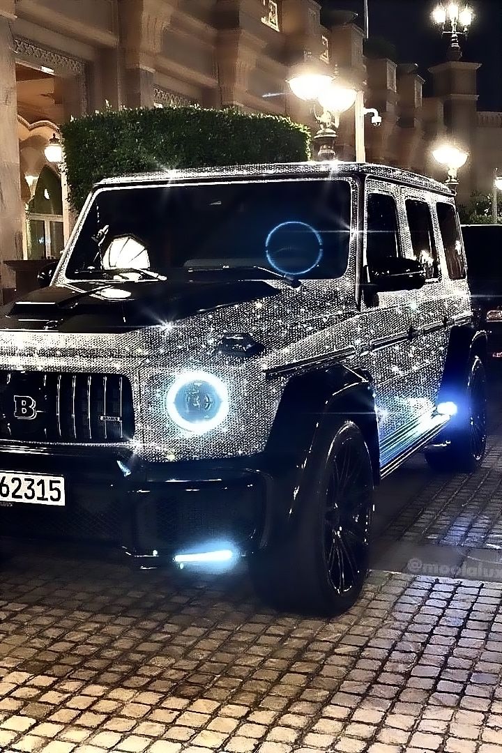 a mercedes g - class parked in front of a building at night