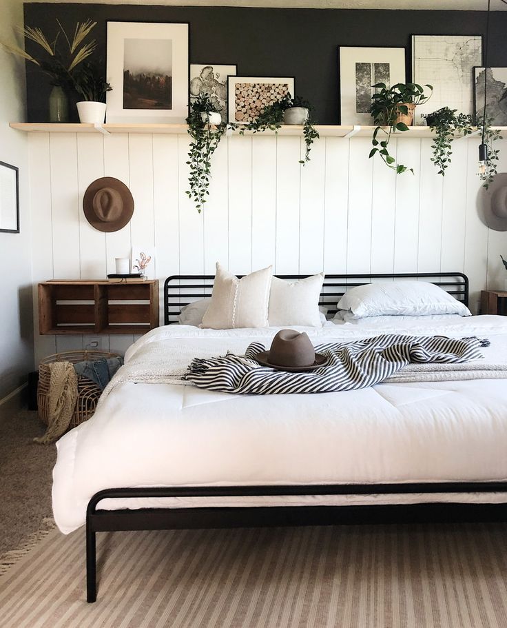 a bed with white sheets, pillows and pictures on the wall above it in a bedroom