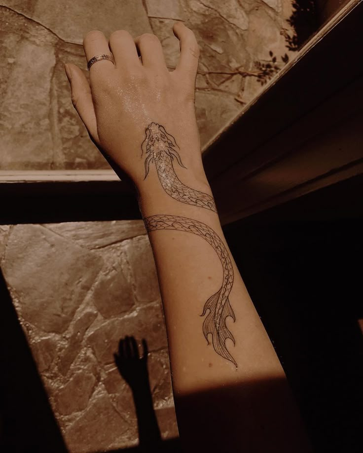 a woman's arm with a tattoo on it and a hand reaching up towards the window