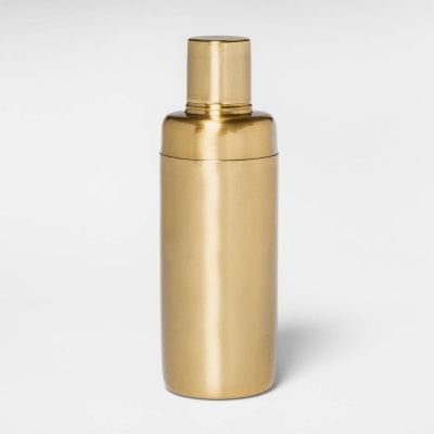 a gold colored metal bottle on a white background, with the lid off and no cap