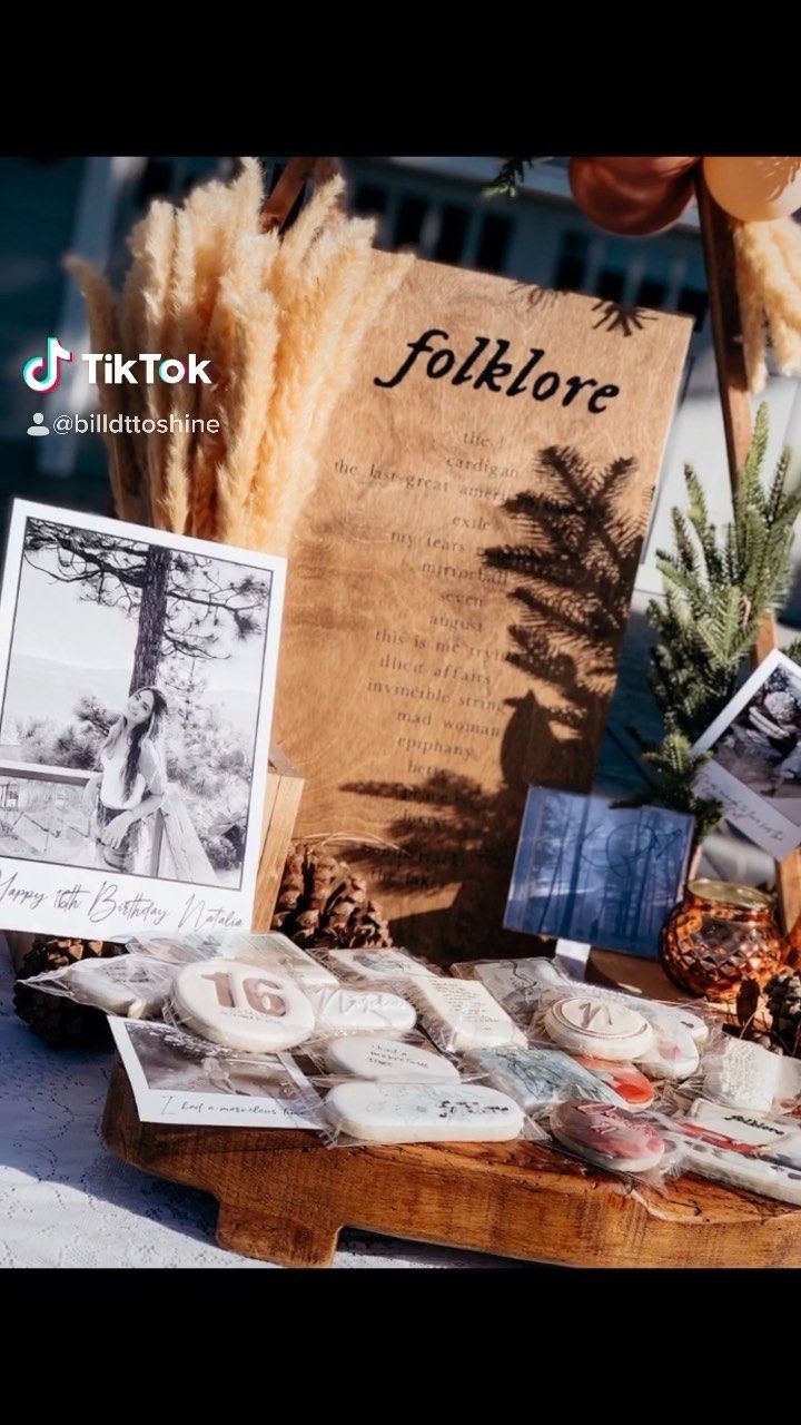 a table topped with lots of food and pictures on top of wooden boards next to pine cones