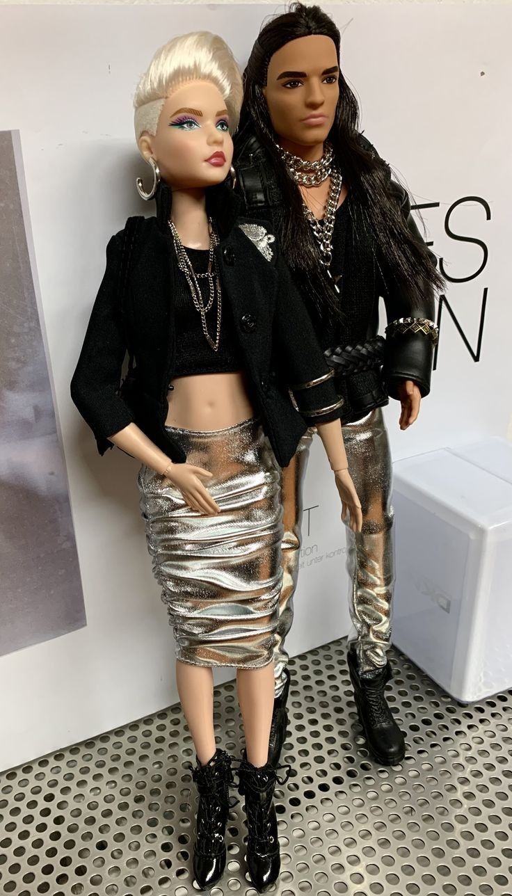 two dolls are standing next to each other in front of a wall with a sign on it