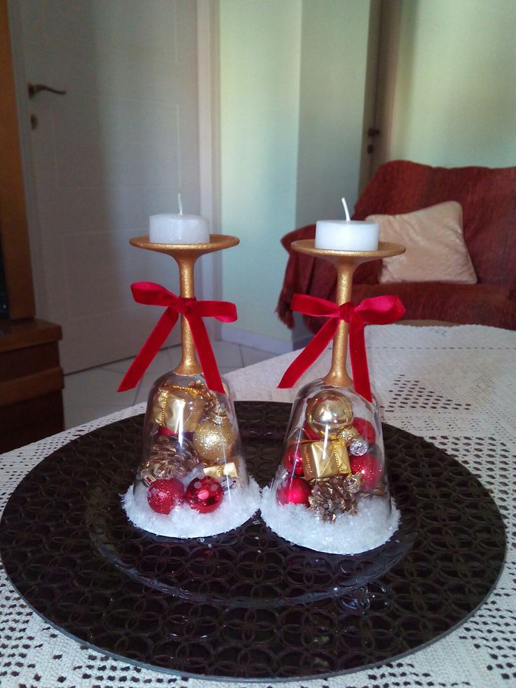 two candles sitting on top of a black plate with red bows and bells in them