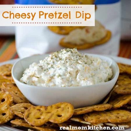 cheesey pretzel dip in a white bowl on a plate with crackers