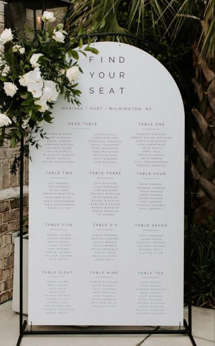 a seating sign with white flowers on it