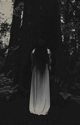 a ghostly woman standing in the middle of a forest with her back turned to the camera