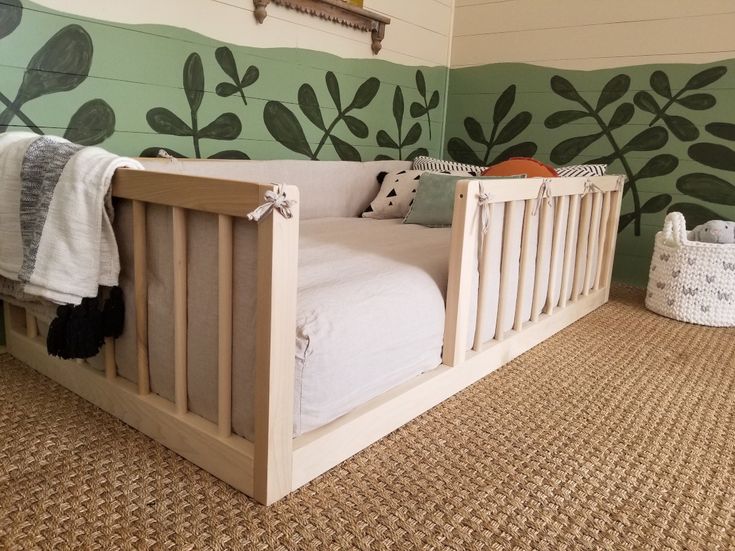 a baby crib in the corner of a room with green leaves painted on the wall