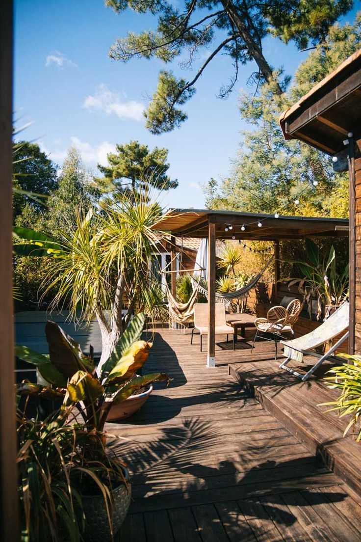 a wooden deck with hammock chairs and potted plants