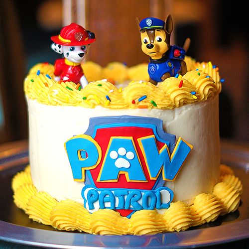 a birthday cake decorated with paw patrol characters and dog figurines on the top