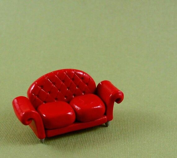 a red toy couch sitting on top of a green floor