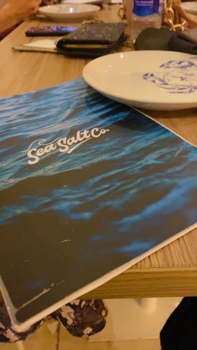 a book sitting on top of a wooden table next to a white plate and water bottle