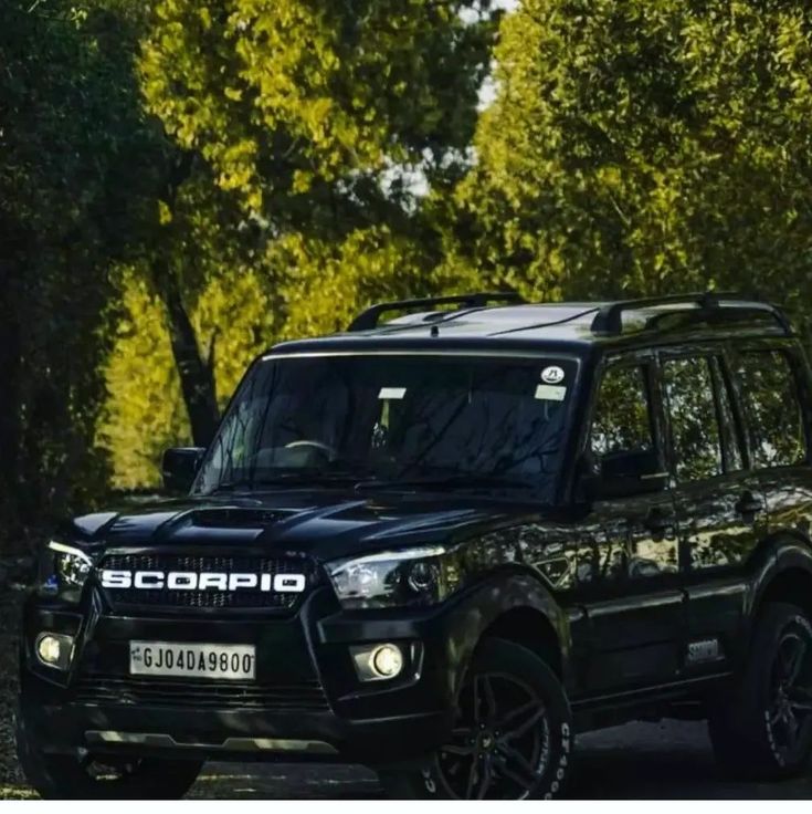 a black suv driving down a dirt road next to trees and bushes with the words scorpion written on it