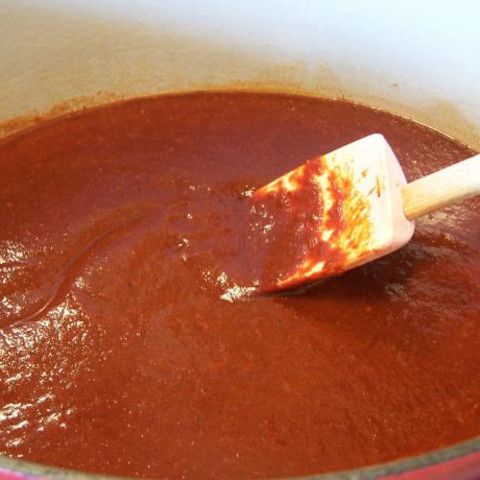 a wooden spoon in a pot filled with red sauce