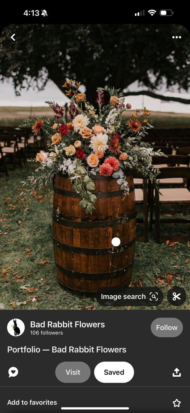 a wooden barrel filled with flowers on top of a field