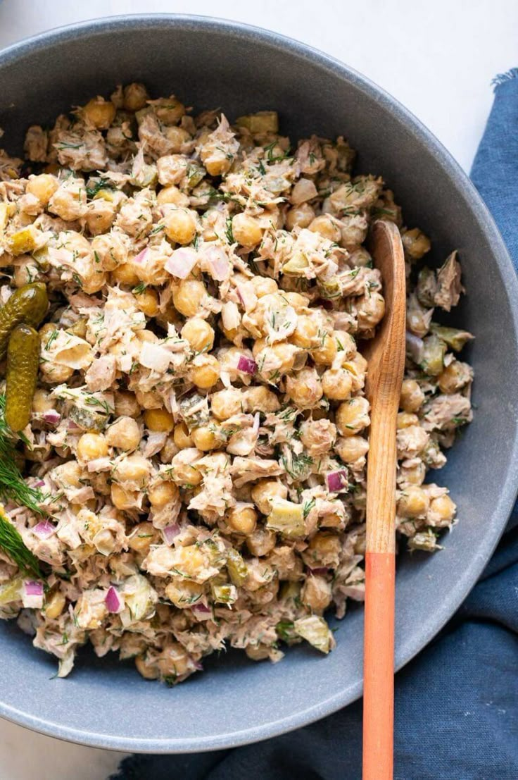 a bowl full of food with a wooden spoon next to it on a blue cloth