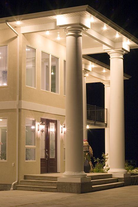 a large house with columns and lights on it