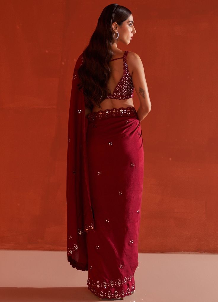 Featuring a maroon silk saree embellished with mirror and tonal silken thread work. It is paired with a sleeveless blouse with mirror and thread work in jaal pattern along with tassel tie-up at the back.Composition : Saree & Blouse: SilkCare: Dry Clean Only and Vacuum Storage All products can be customised for sleeves, length of blouse and neck design Delivery : 4-6 weeks as the product is hand crafted. Check Size Guide or choose MySize for free customisation (All Sizes above XL can be made at 15% additional cost) For more information and sizes please contact fabiliciousfashion@gmail.com or visit our Copenhagen studio.About the Designer : Angad Singh's journey in the world of fashion started with at an early age as he grew up in a family business that was immersed in couture. Seeking to ex Maroon Silk Saree, Mirror Work Saree, Saree And Blouse, Mirror Embroidery, Padded Blouse, Hem Blouse, Work Sarees, Wedding Destination, Mirror Work