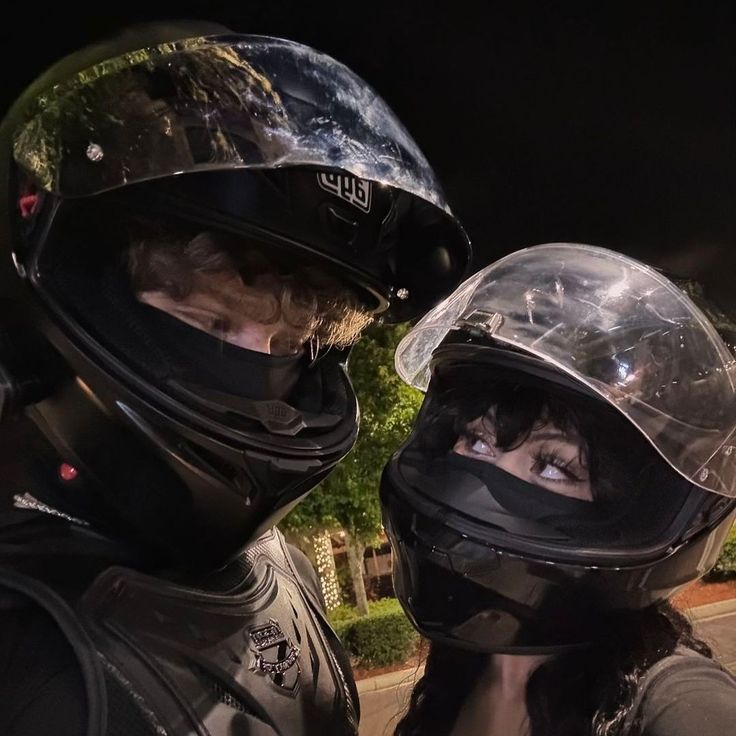 two people wearing helmets standing next to each other