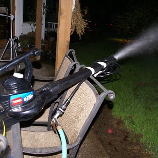 a bicycle sprinkles water on the back of a bench in front of a house