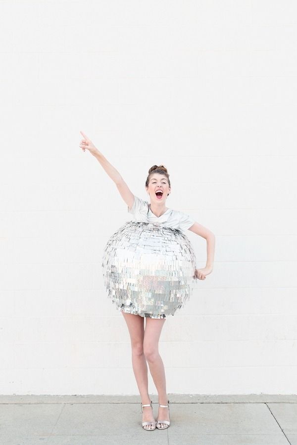 a woman wearing a silver sequin dress and holding her arms in the air