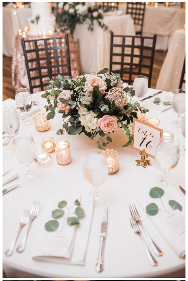 the table is set with white linens, silverware and pink flowers on it