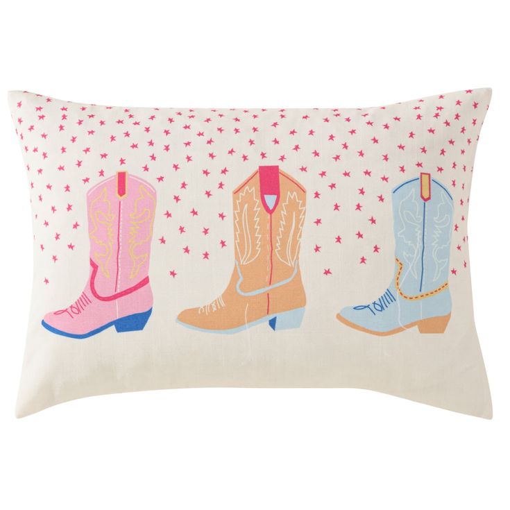 three cowboy boots on a white pillow with pink, blue and yellow stars in the background