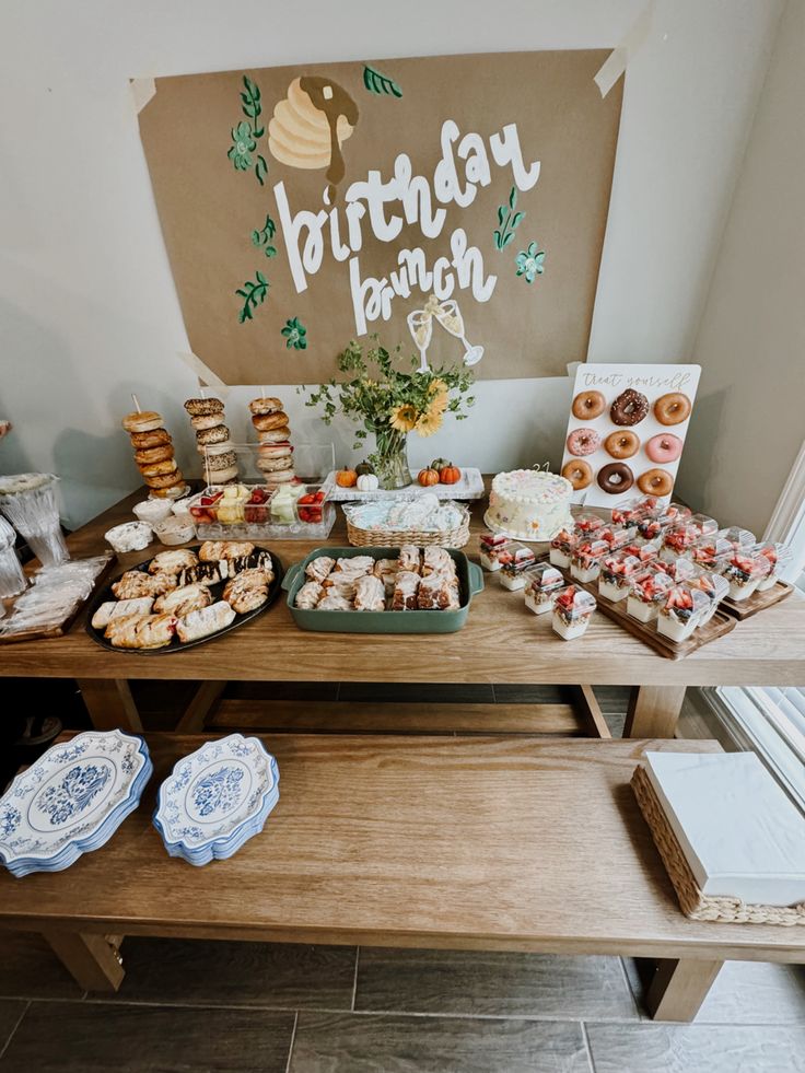 a wooden table topped with lots of cakes and pastries next to a sign that says birthday banquet