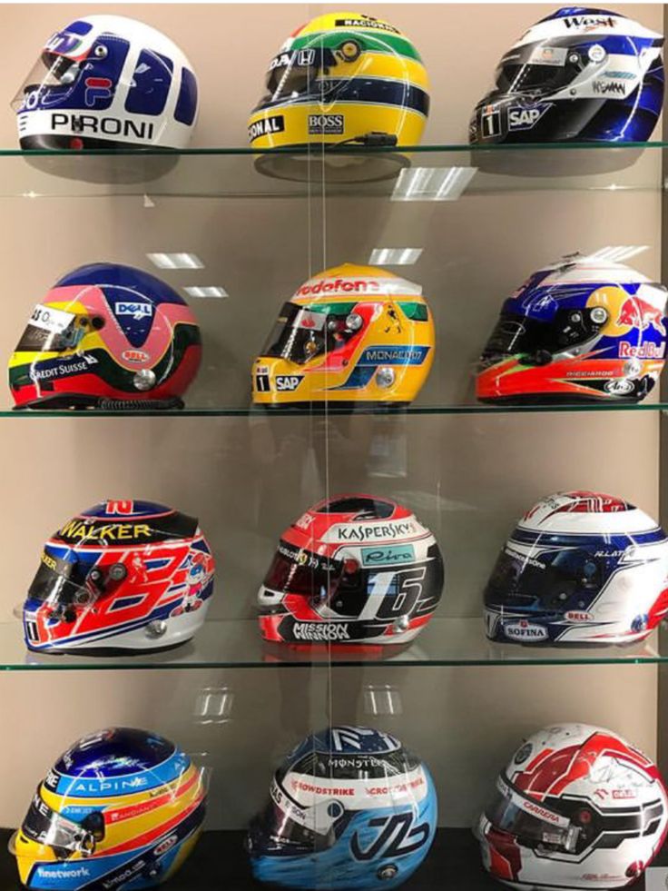 several helmets are displayed on glass shelves in a display case at a motorcycle shop,