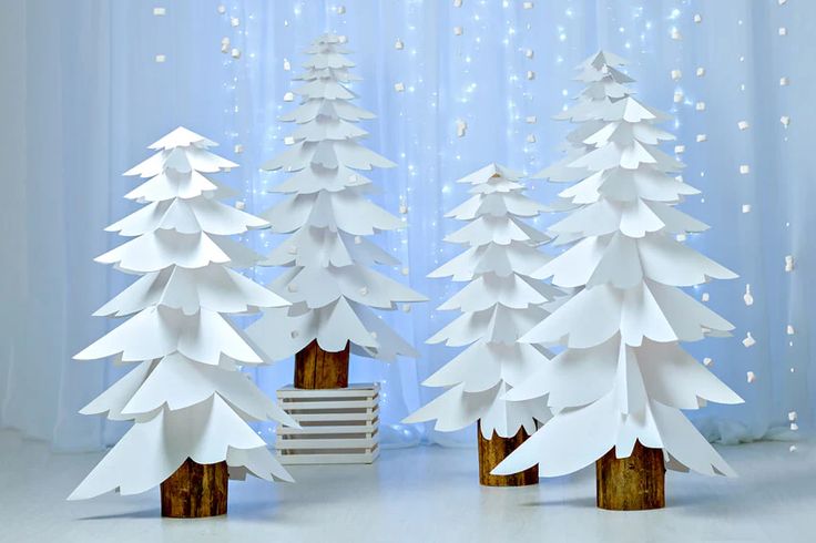 three white paper christmas trees in front of a curtain