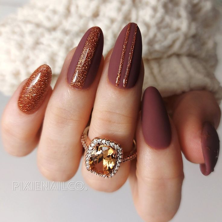 a woman's hand with some brown and gold nail polishes on her nails