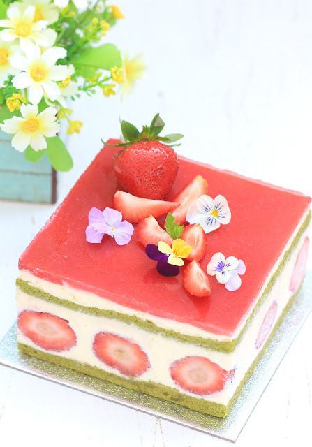 a piece of cake with strawberries and flowers on it sitting next to a potted plant