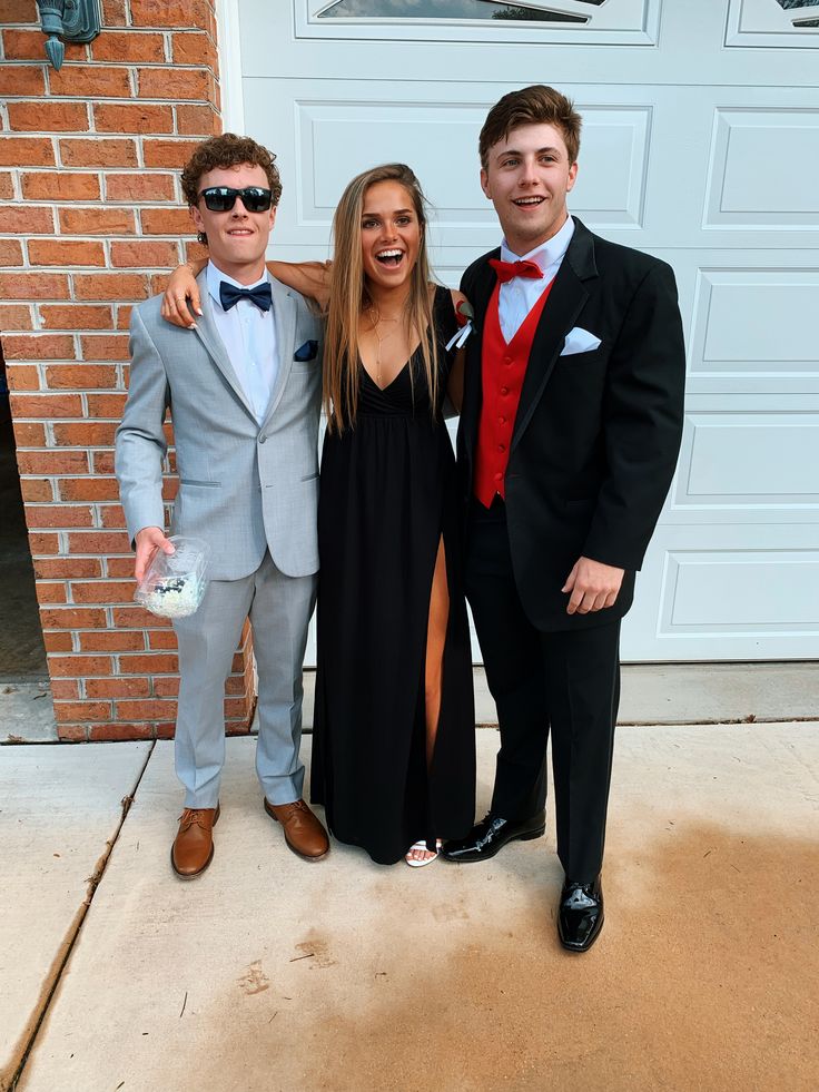 three people dressed up in formal wear posing for a photo together on the front porch