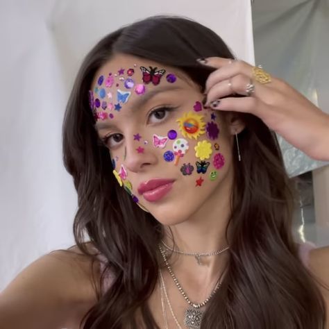 a woman with flowers painted on her face is looking at the camera and she has long dark hair