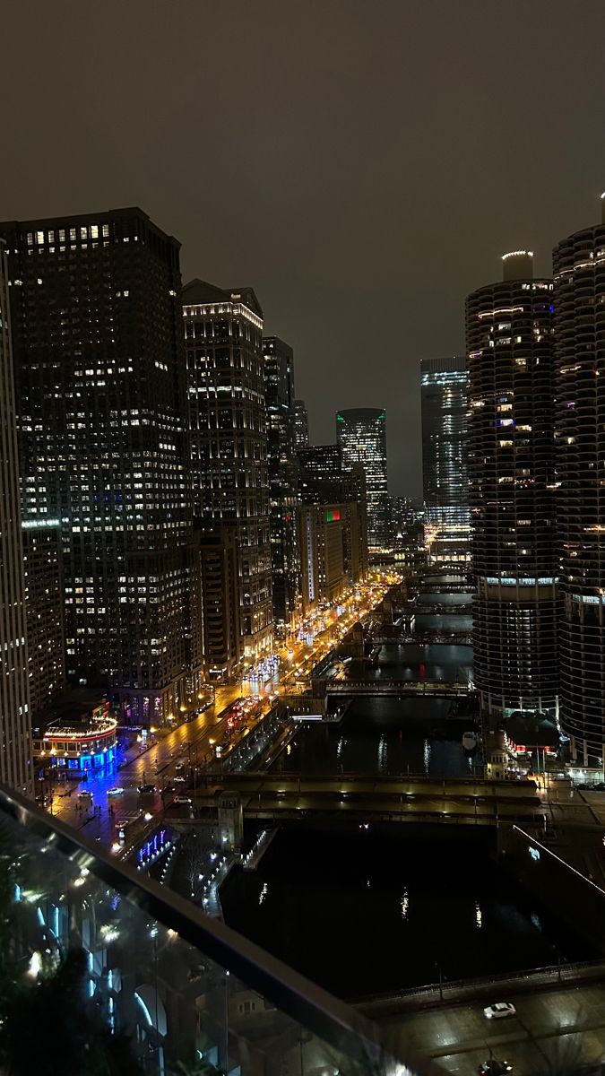 the city skyline is lit up at night with lights on and buildings in the foreground