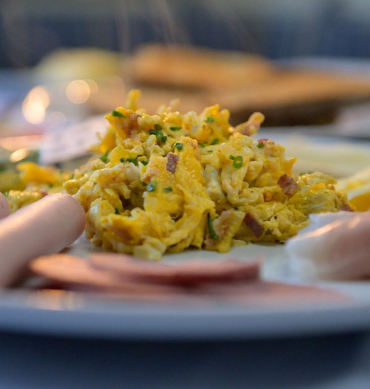 a plate with some food on it and someone's hand reaching for the food