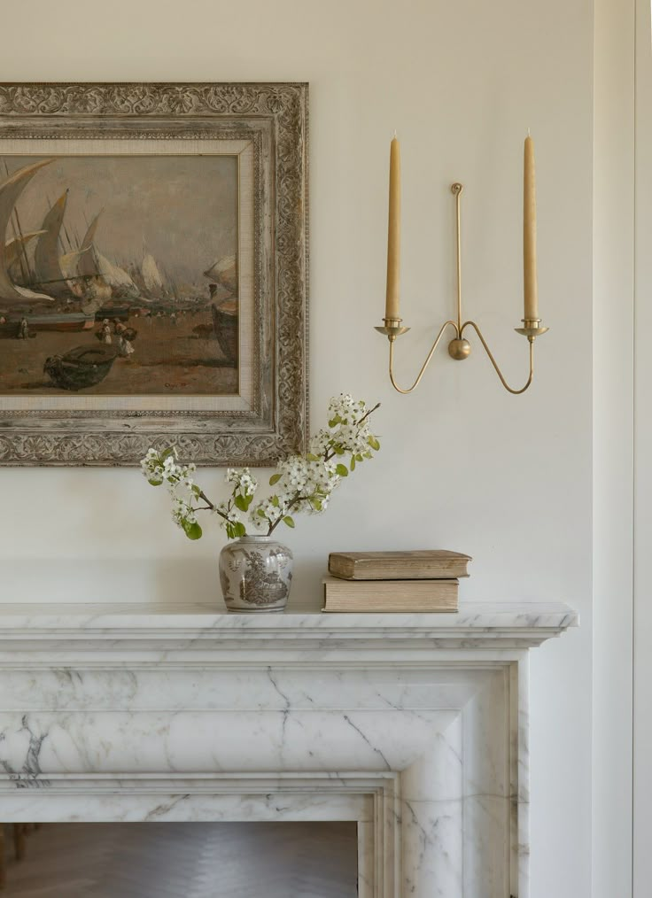 a painting on the wall above a fireplace in a room with white walls and marble mantle