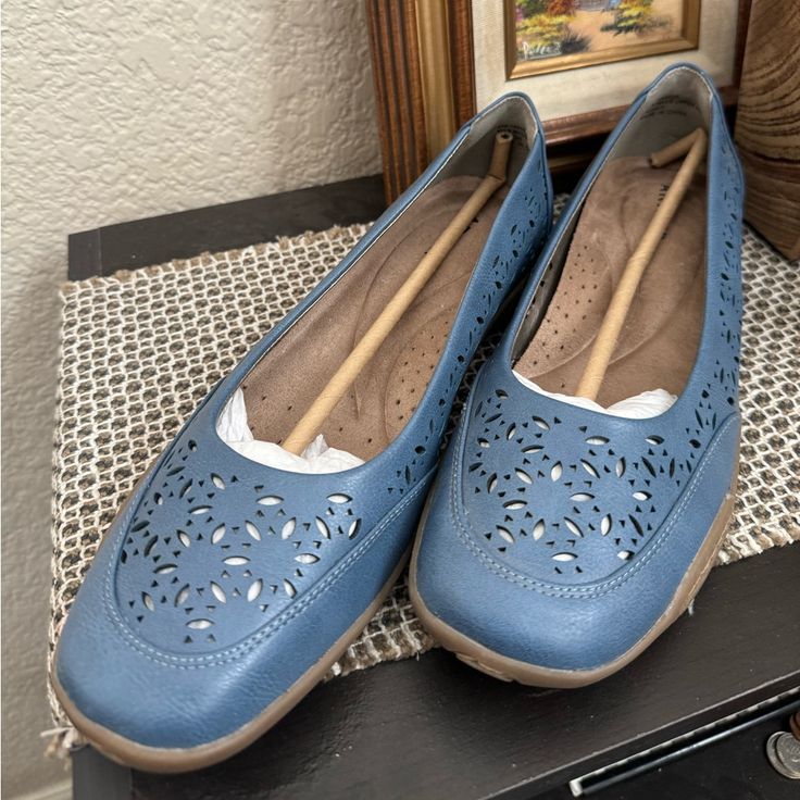 a pair of blue shoes sitting on top of a table next to a framed painting