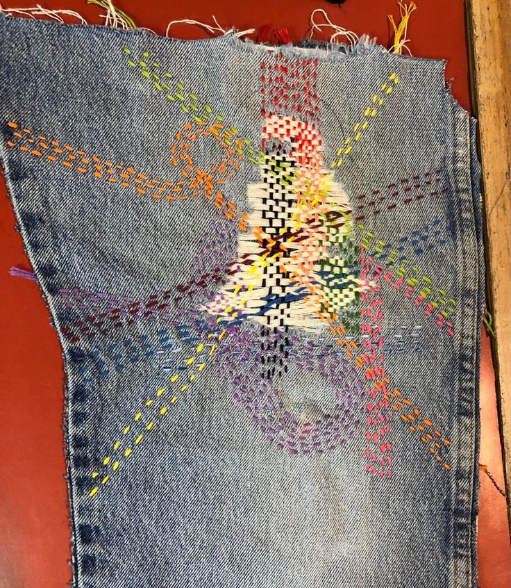 an old pair of jeans has been stitched together with different colored threads on it