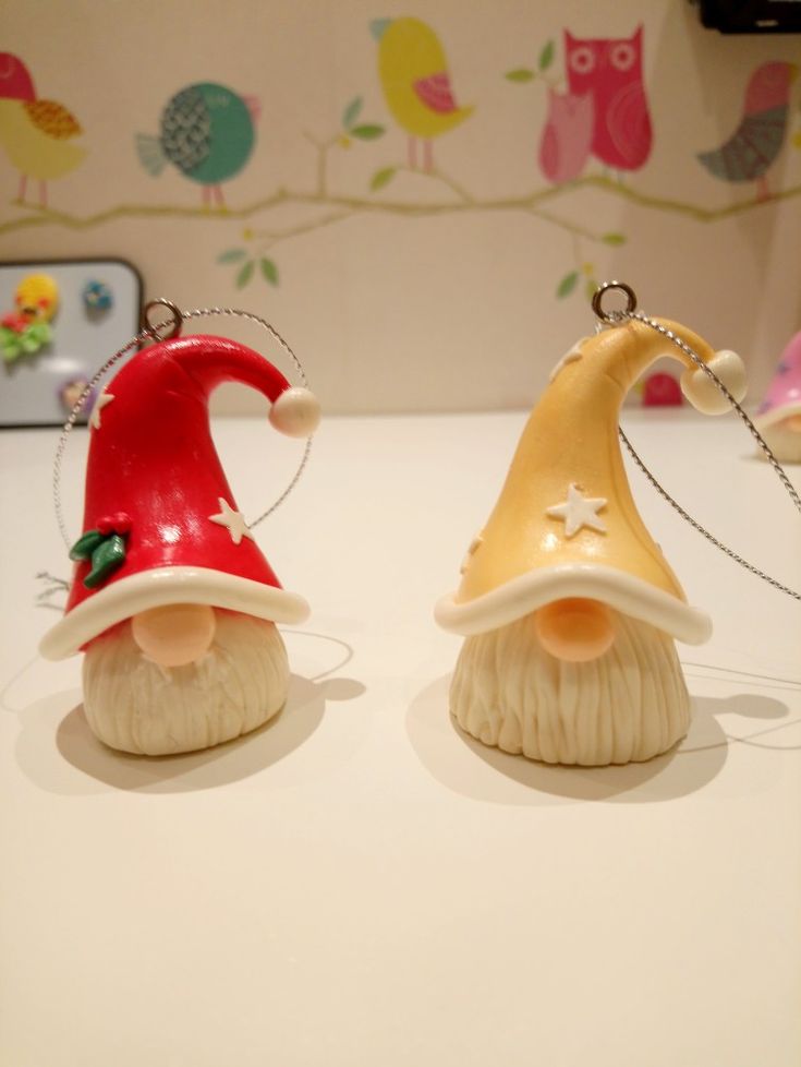 two christmas gnome figurines sitting on top of a white table next to each other