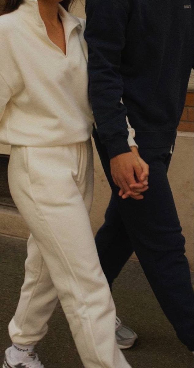 a man and woman are walking down the street together, one is wearing white pants