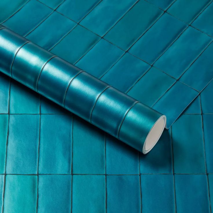 a roll of blue tile sitting on top of a tiled floor next to a wall