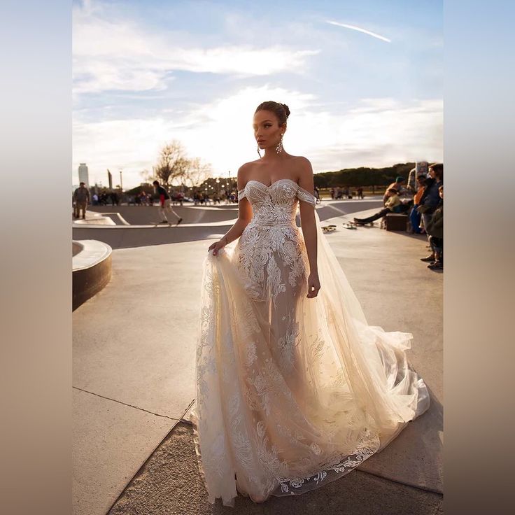 a woman in a wedding dress is walking down the street with her hand on her hip