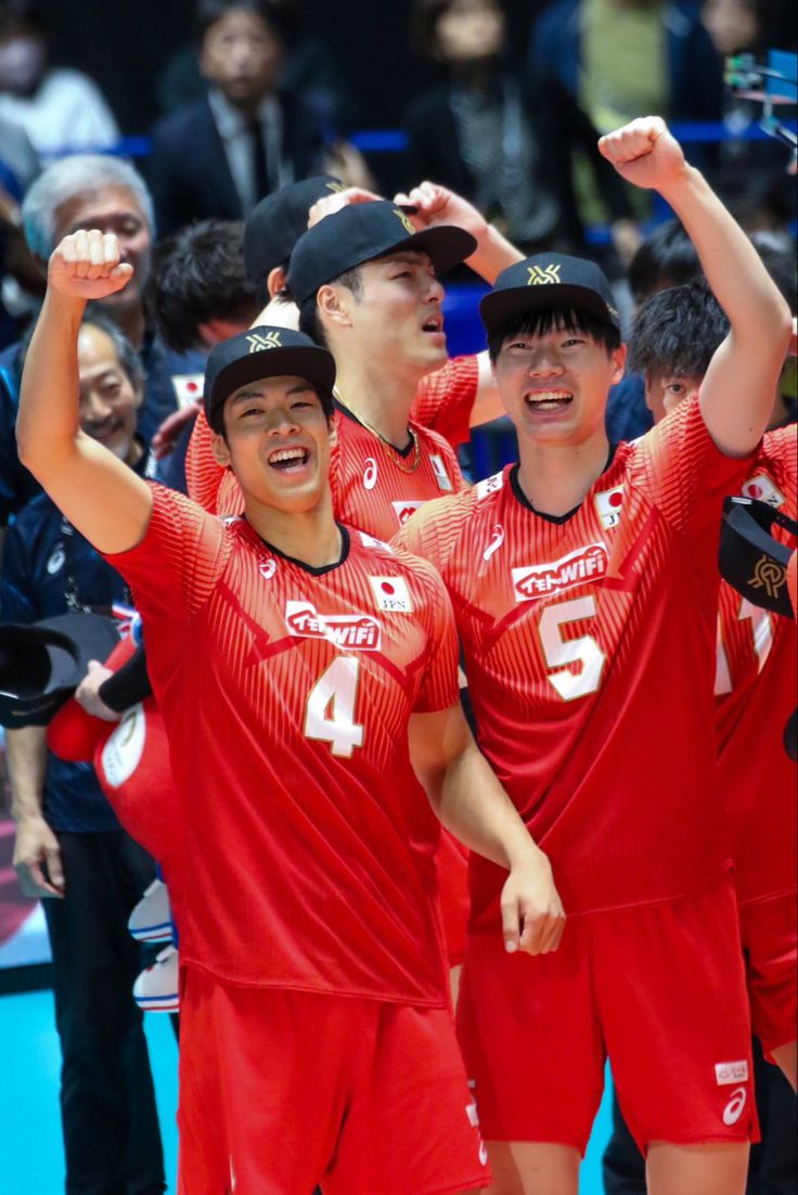 three men in red uniforms standing next to each other with their hands up and one man holding his head