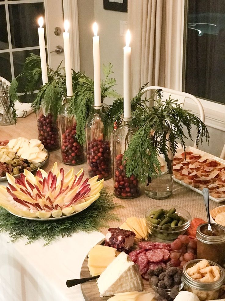 a table topped with lots of different types of food and candles on top of it