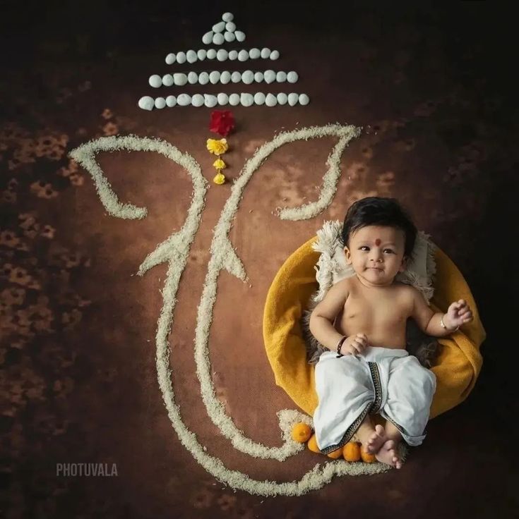 a baby is sitting on a yellow chair in front of a sign that says happy diwali