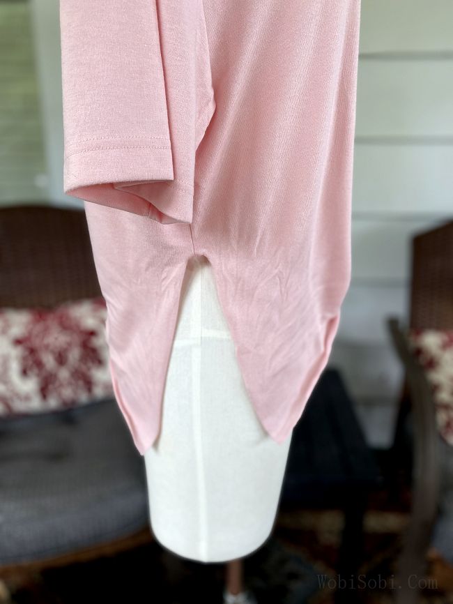 a pink shirt is hanging on a white mannequin in front of a couch