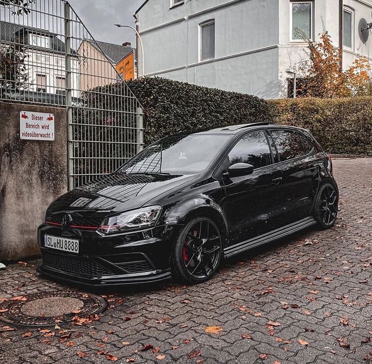 a black car parked in front of a fence