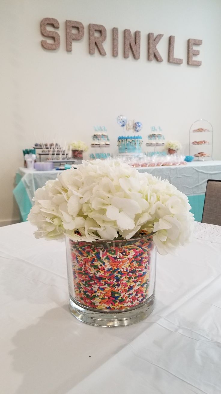 a vase filled with white flowers and sprinkles on top of a table