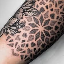 a person with a tattoo on their arm that has an intricate pattern and leaves in the middle